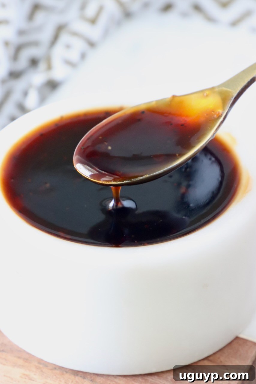 A small white bowl filled with glossy, rich Korean BBQ sauce, with a miniature gold spoon dipped into it, indicating its delicious consistency.