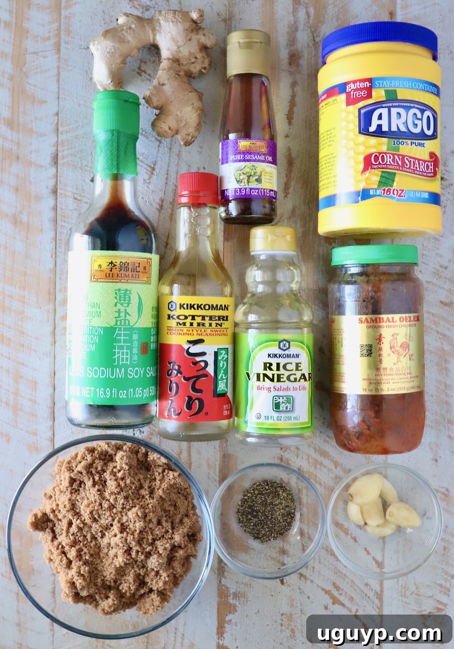 A selection of fresh ingredients for Korean BBQ sauce laid out on a clean white wooden board, including soy sauce, brown sugar, garlic, ginger, and chili paste.
