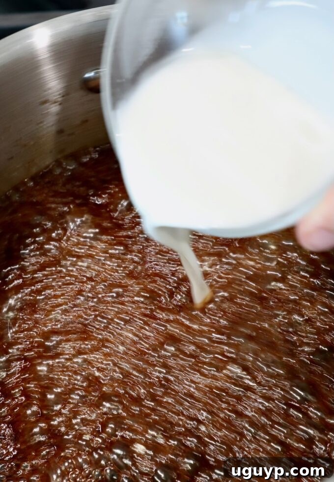 A small glass bowl pouring a white cornstarch slurry into the simmering Korean BBQ sauce in a pot, illustrating the thickening step.