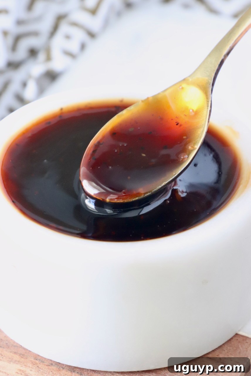 A close-up shot of Korean BBQ sauce in a small white bowl, highlighting its rich texture and color, with a small spoon ready to scoop.