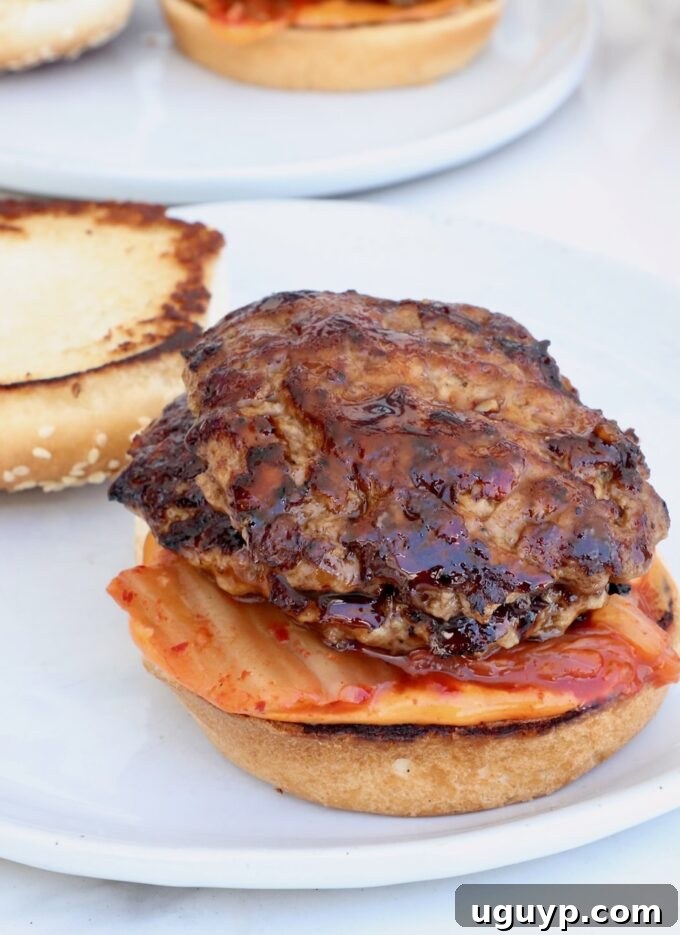 hamburger bun on a plate topped with kimchi and bbq glazed burger patties