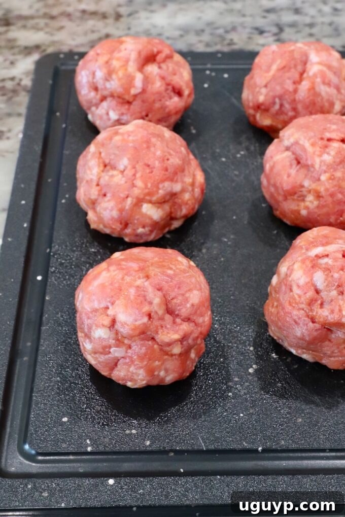 balls of seasoned ground beef and pork on a cutting board
