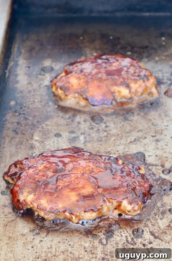burger patties topped with korean bbq sauce on a griddle