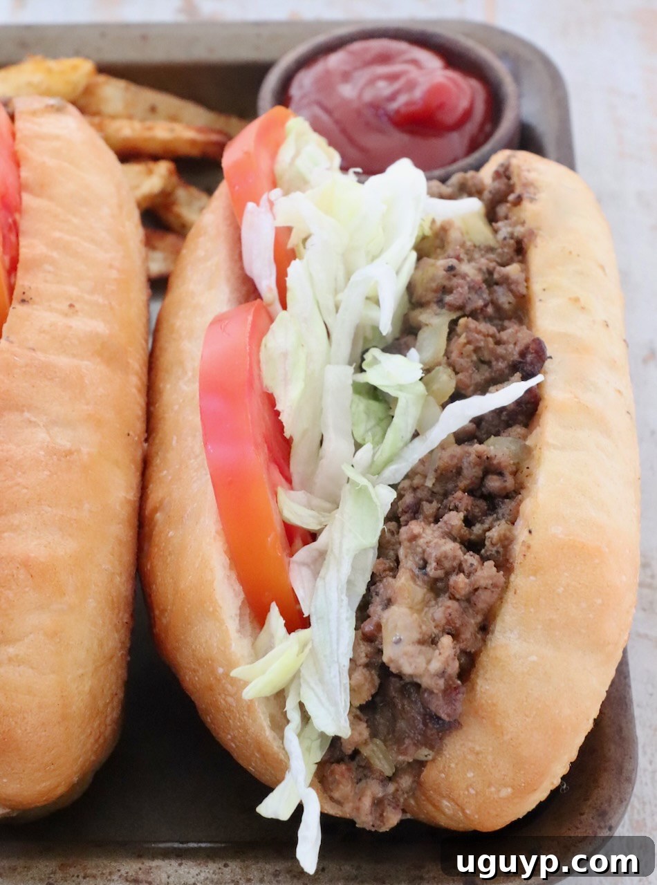 A single, perfectly crafted chopped cheese sandwich sits on a metal baking sheet, with a small bowl of ketchup in the background, ready for a delicious meal.