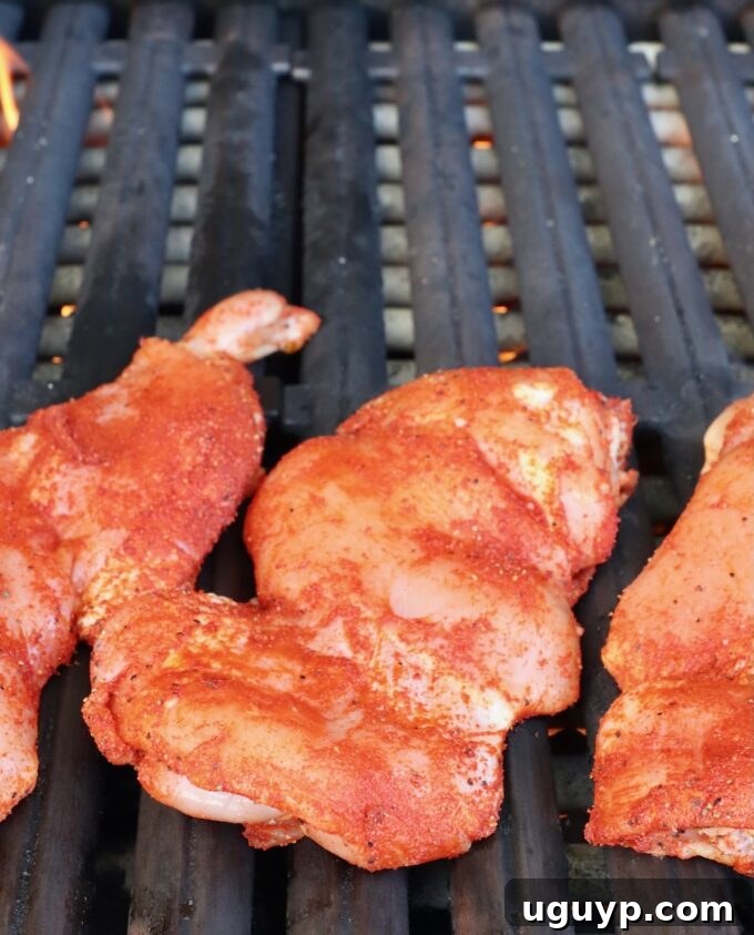 Seasoned chicken thighs carefully placed onto a hot grill grate, ready for cooking.