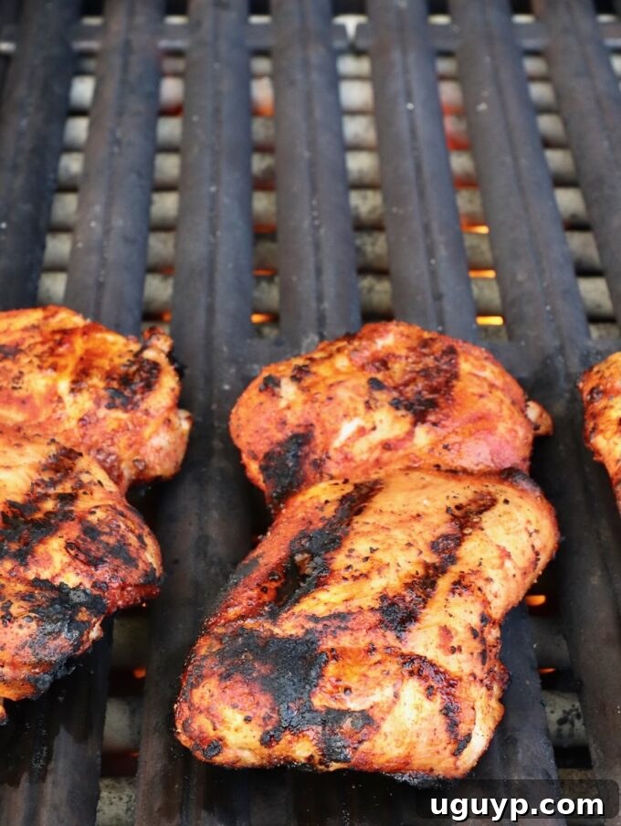 Grilled chicken thighs developing a beautiful char and cooked texture on the grill.