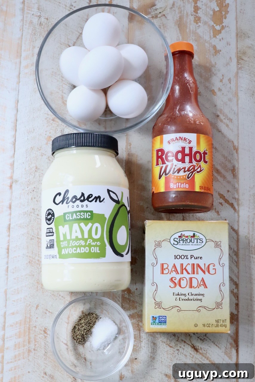 ingredients for buffalo deviled eggs on a white wood board