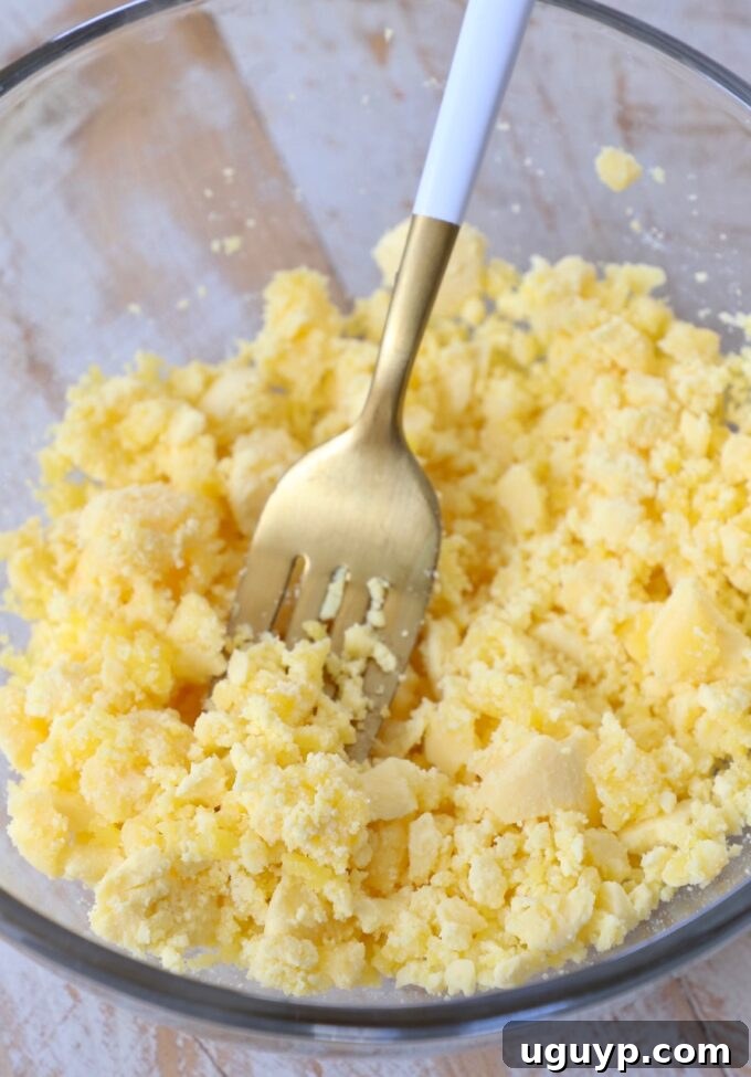 smashed egg yolks in glass bowl with fork
