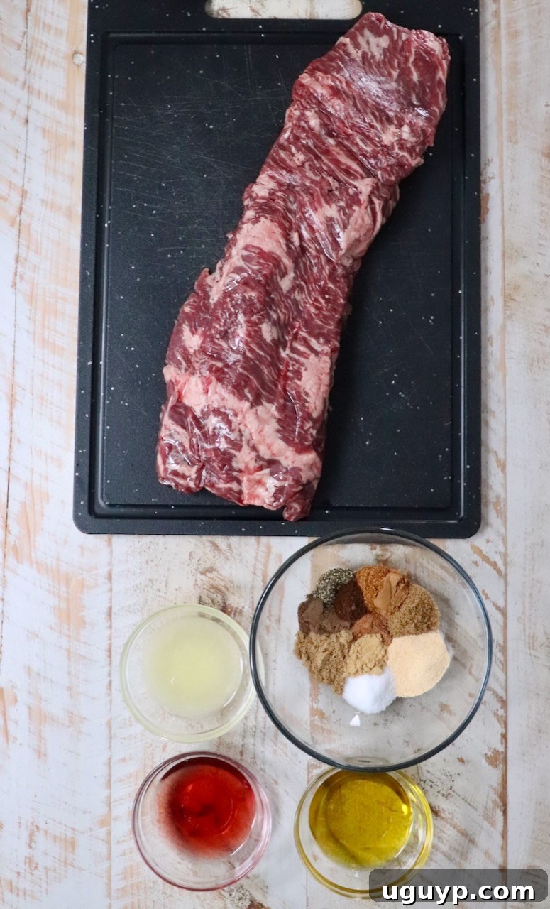 ingredients for beef shawarma laid out on a white wooden board, including spices, oil, vinegar, lemon, and skirt steak