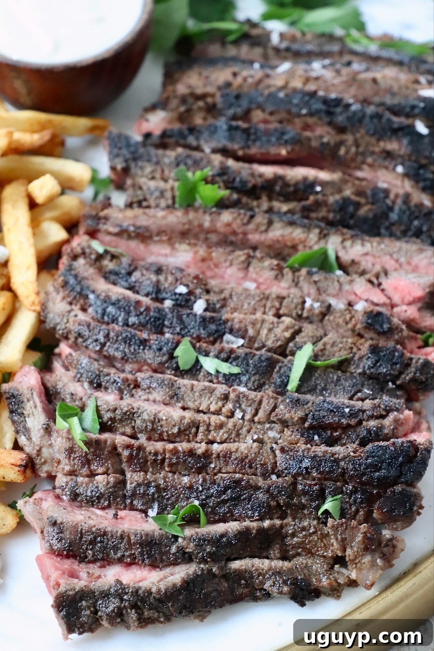 sliced beef shawarma on a platter next to crispy french fries and a small bowl of creamy sauce on the side