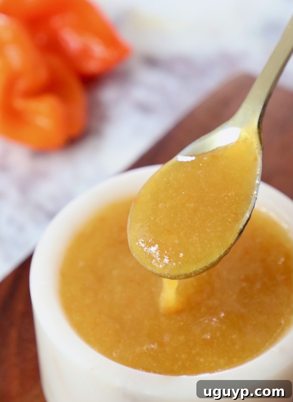 A close-up shot of rich mango habanero sauce, presented elegantly in a small bowl with a spoon, highlighting its smooth texture and appetizing color.