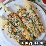 Grilled corn on the cob on a plate, elegantly topped with blue cheese crumbles and freshly chopped cilantro, highlighting the vibrant colors and appealing texture.