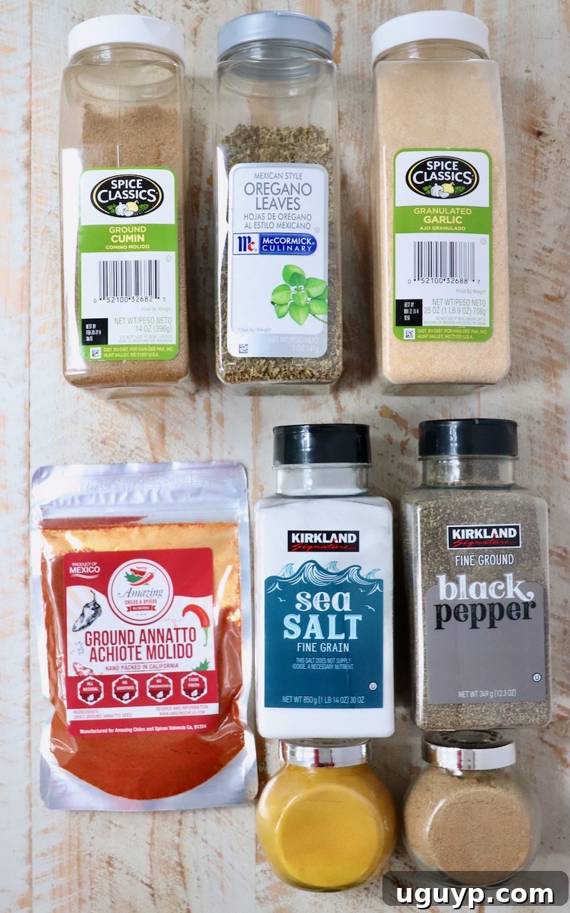 Eight small containers filled with individual spices laid out on a white wooden board, showcasing the ingredients needed for Sazon seasoning.