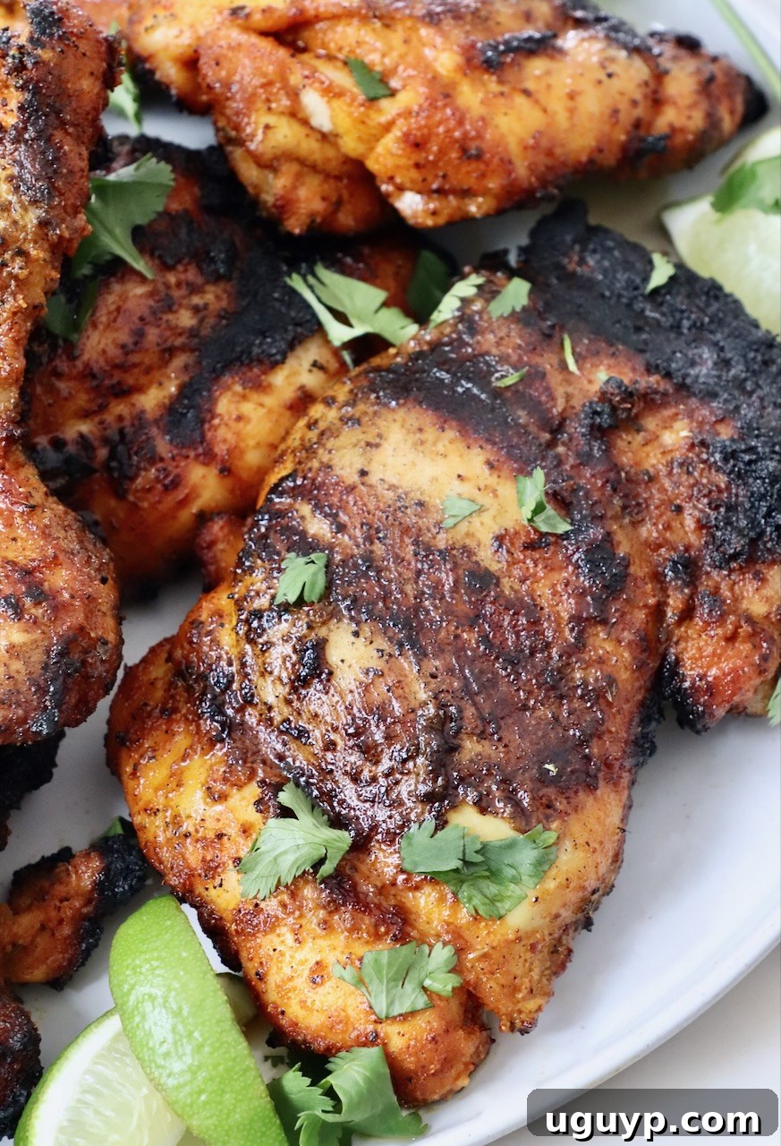 Perfectly grilled chicken thighs stacked on a plate, garnished with fresh lime wedges, showcasing a delicious meal seasoned with Sazon.
