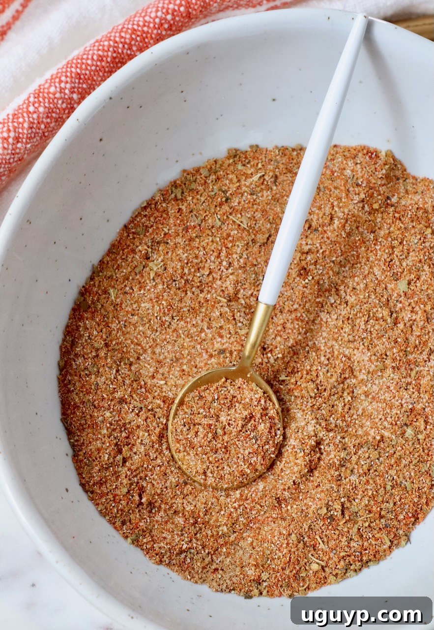 A bowl of vibrant Sazon seasoning with a small spoon, illustrating the finely mixed spices ready for use.