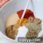 A beautiful array of Sazon spices separated in a bowl with a small spoon, ready for mixing.