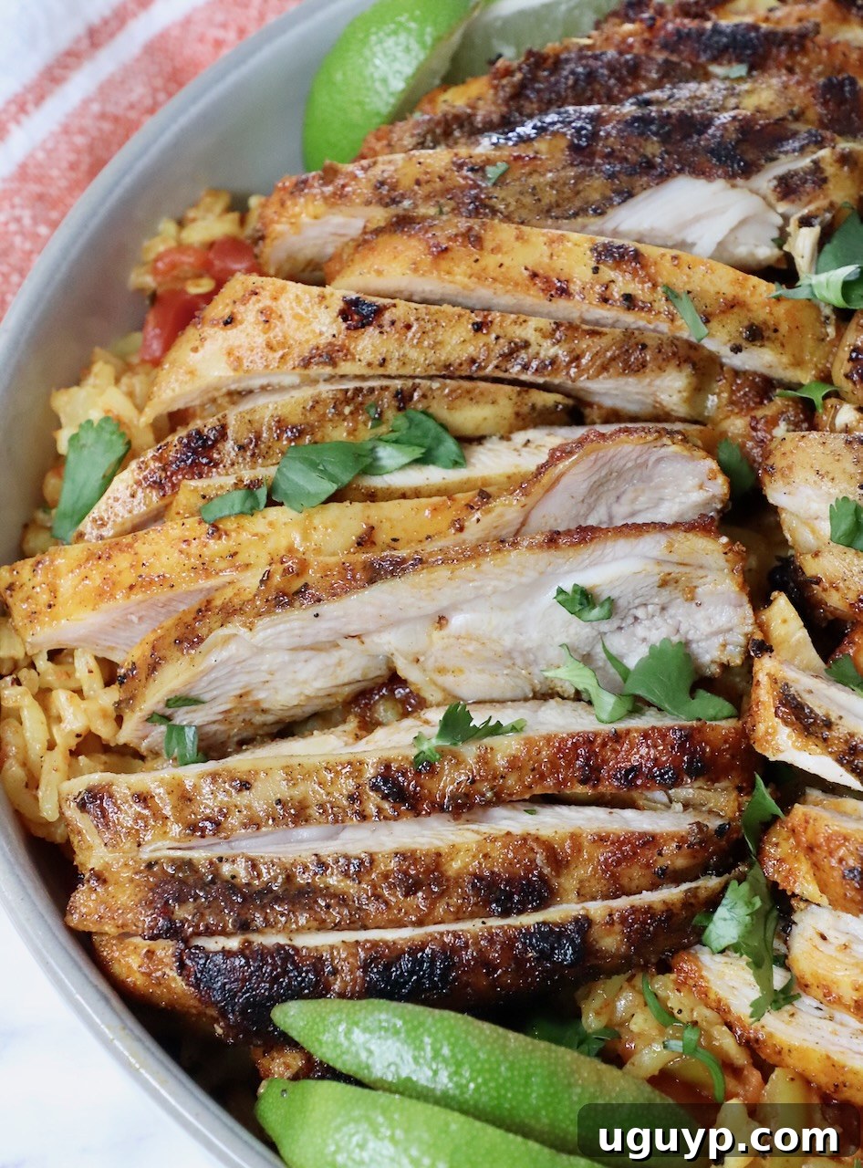 sliced grilled chicken thighs in a bowl with rice and lime wedges