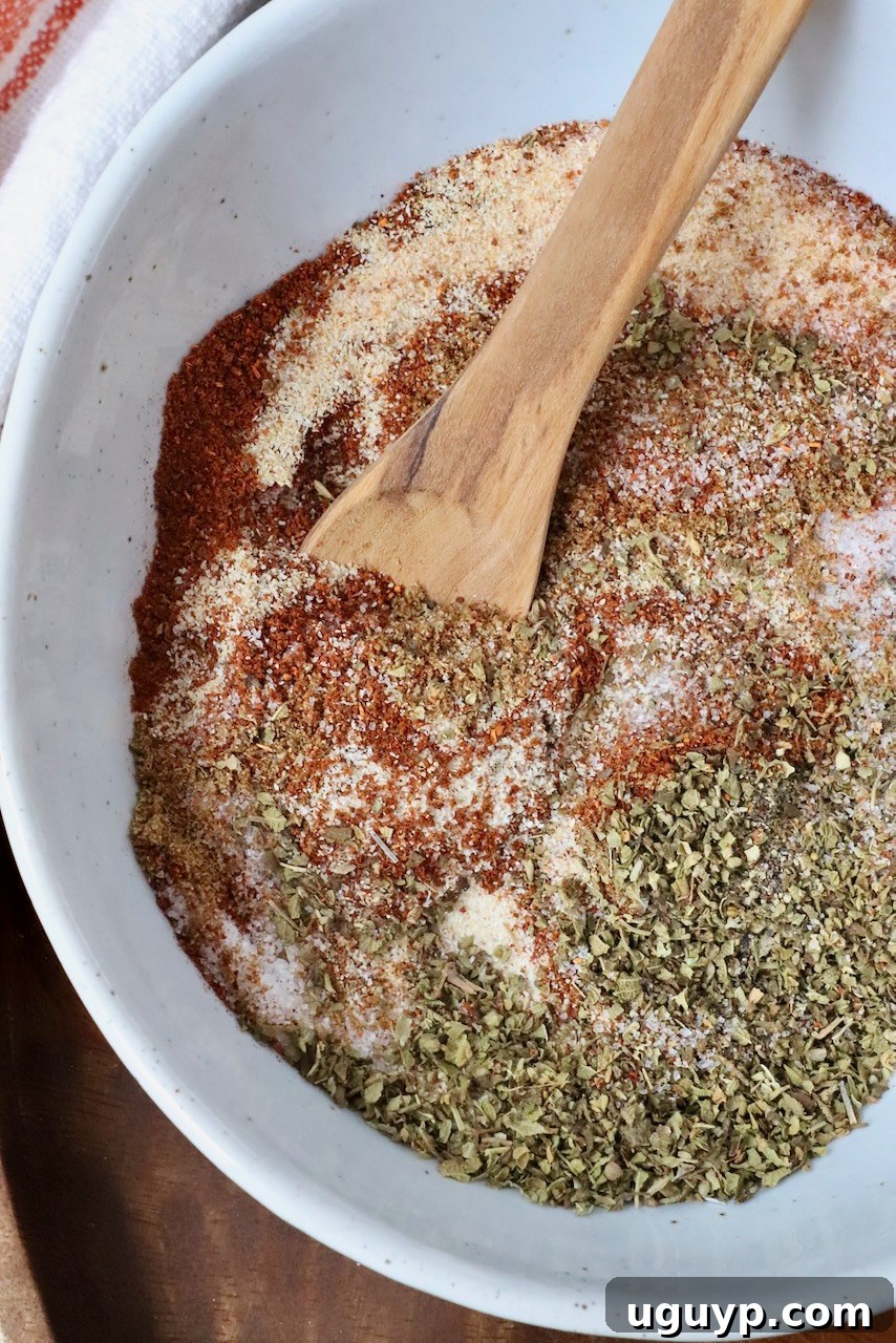 Carnitas seasoning mixed together in a bowl with a wooden spoon, ready for use.