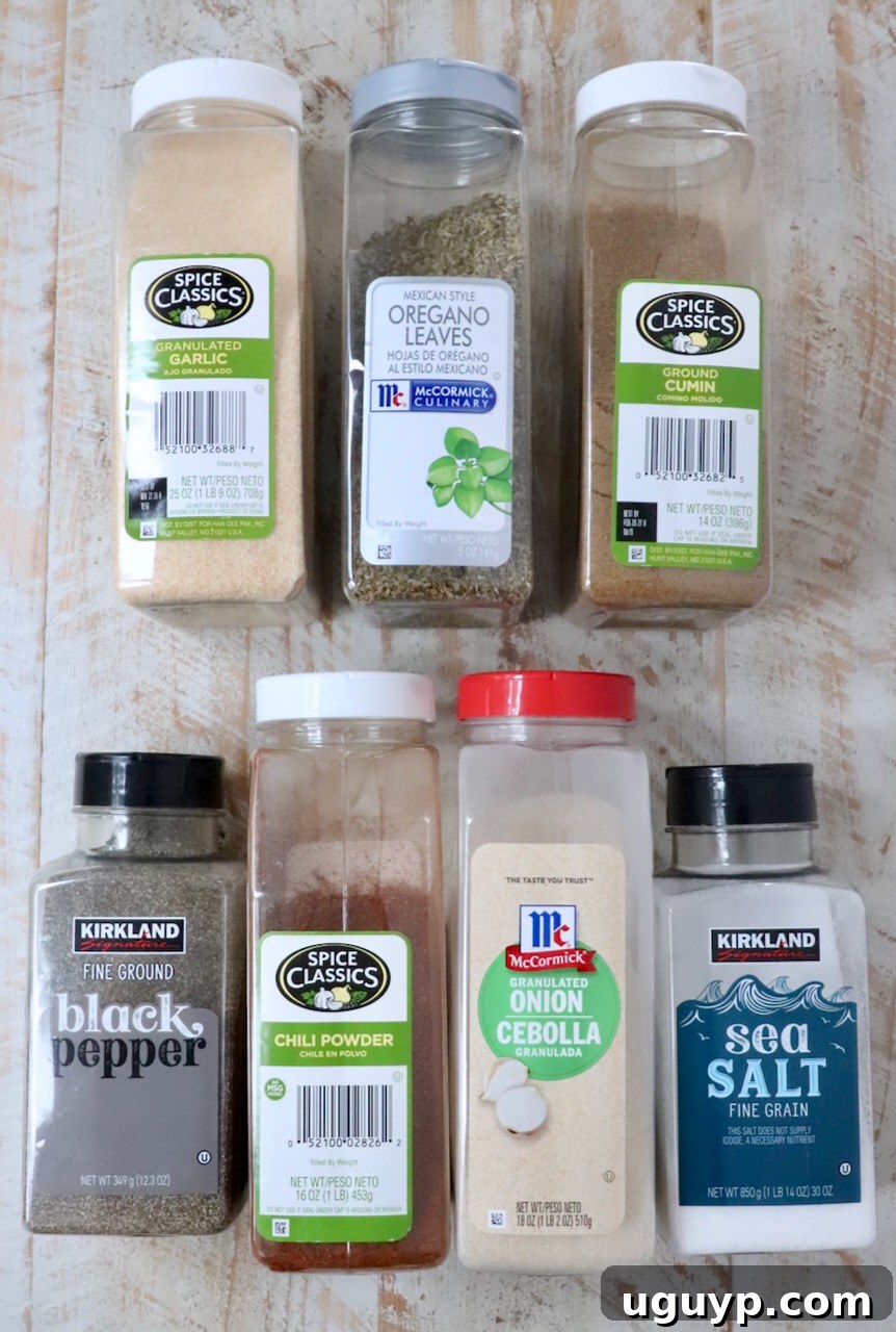 A collection of essential spices in plastic containers, neatly lined up on a rustic white wooden board, ready for blending.