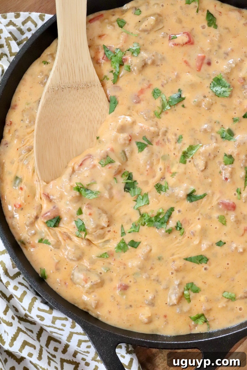 smoked queso dip in a skillet with a wooden spoon
