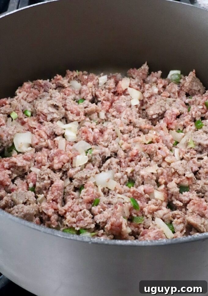 cooked sausage in a large pot with diced onions and jalapenos