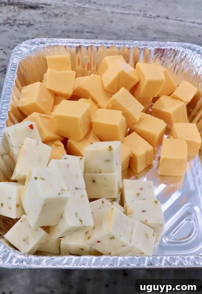 cubes of Velveeta cheese and pepper jack cheese in an aluminum foil pan