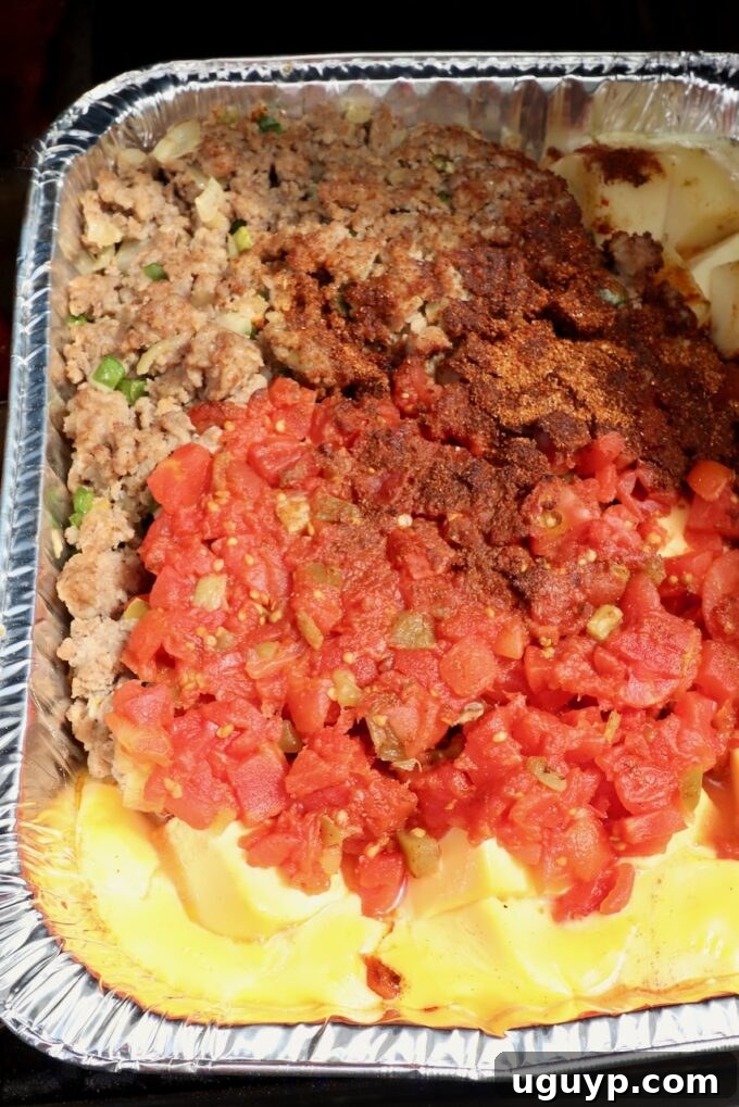melted cheese, cooked, crumbled sausage, diced tomatoes and chili seasoning in an aluminum pan on a smoker