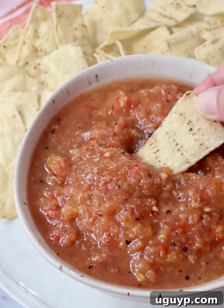 hand dipping a tortilla chip in a bowl of peach salsa, showcasing the vibrant colors and chunky texture of the fresh salsa