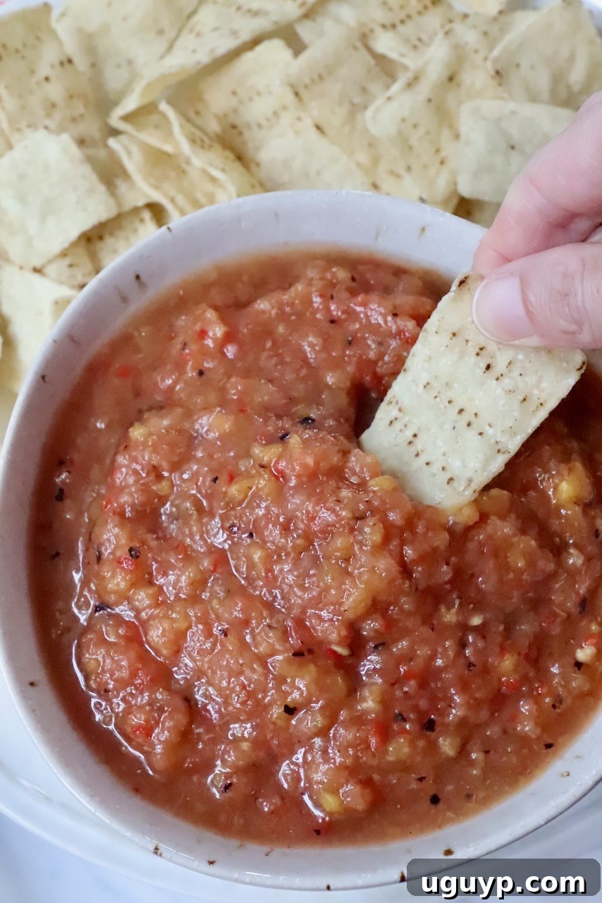 hand dipping a tortilla chip into a bowl of fresh peach salsa, highlighting the inviting texture