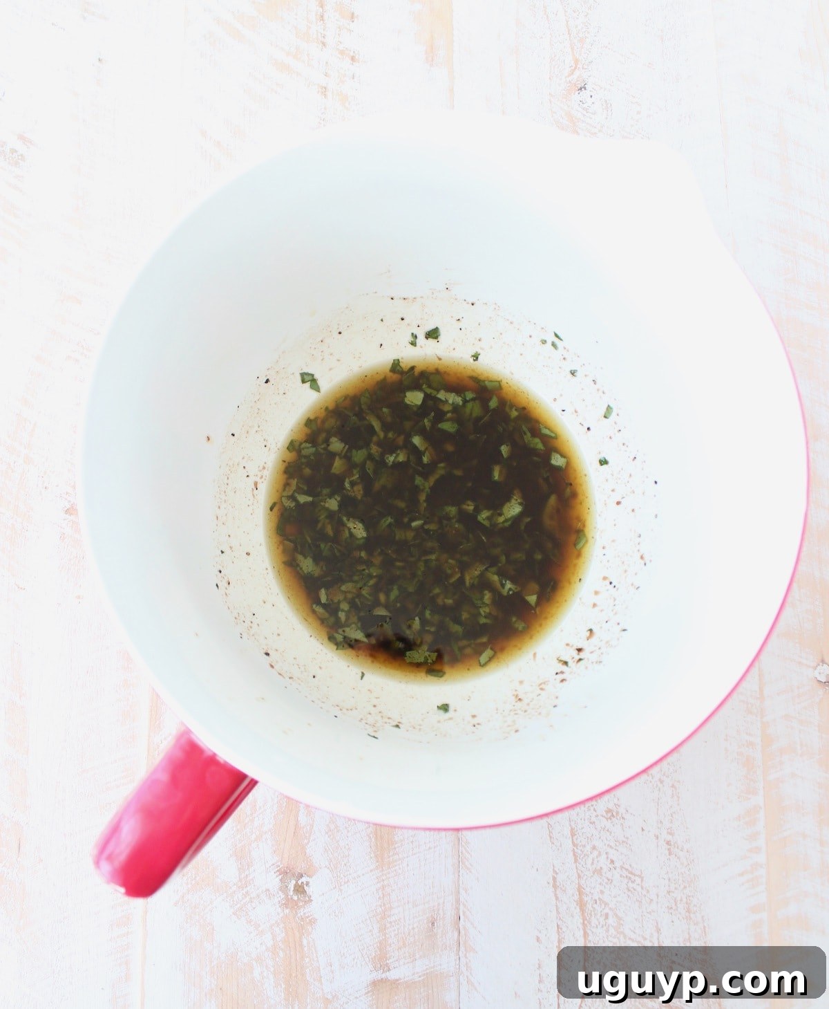 A vibrant lemon balsamic herb dressing in a bowl, made with olive oil, basil, parsley, balsamic vinegar, lemon juice, salt, and pepper.