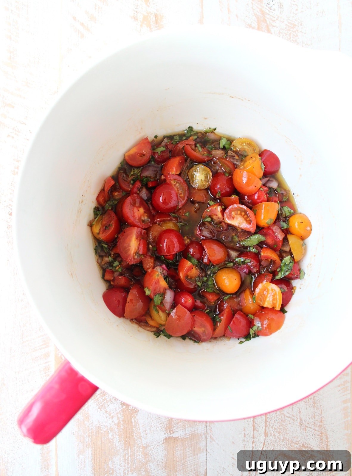 Halved cherry tomatoes added to the dressing with sautéed onions, peppers, and garlic, ready for marination.