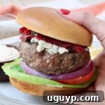 hand holding a lamb burger on a bun over a plate