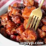 Pork belly burnt ends in a bowl with a fork in one piece of pork belly.