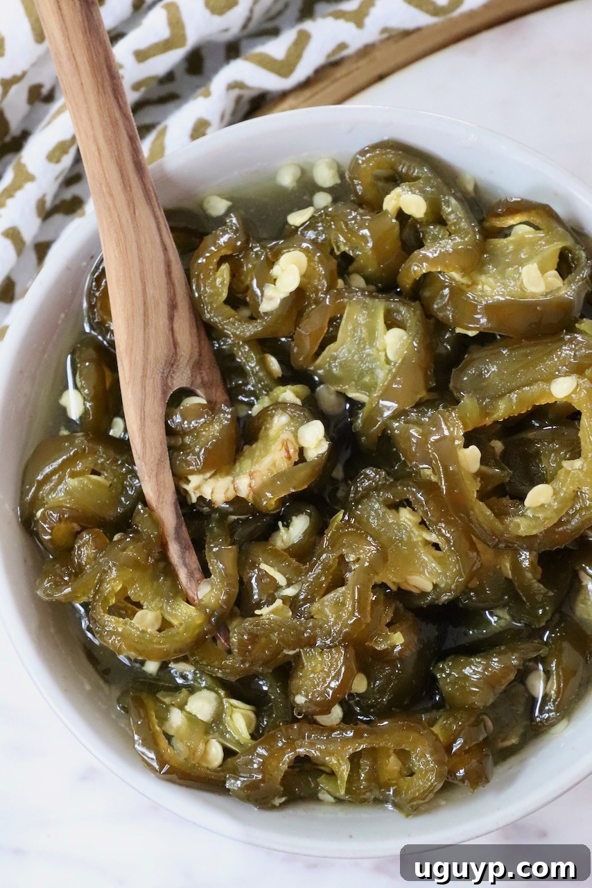 candied jalapenos in a bowl with a wooden fork
