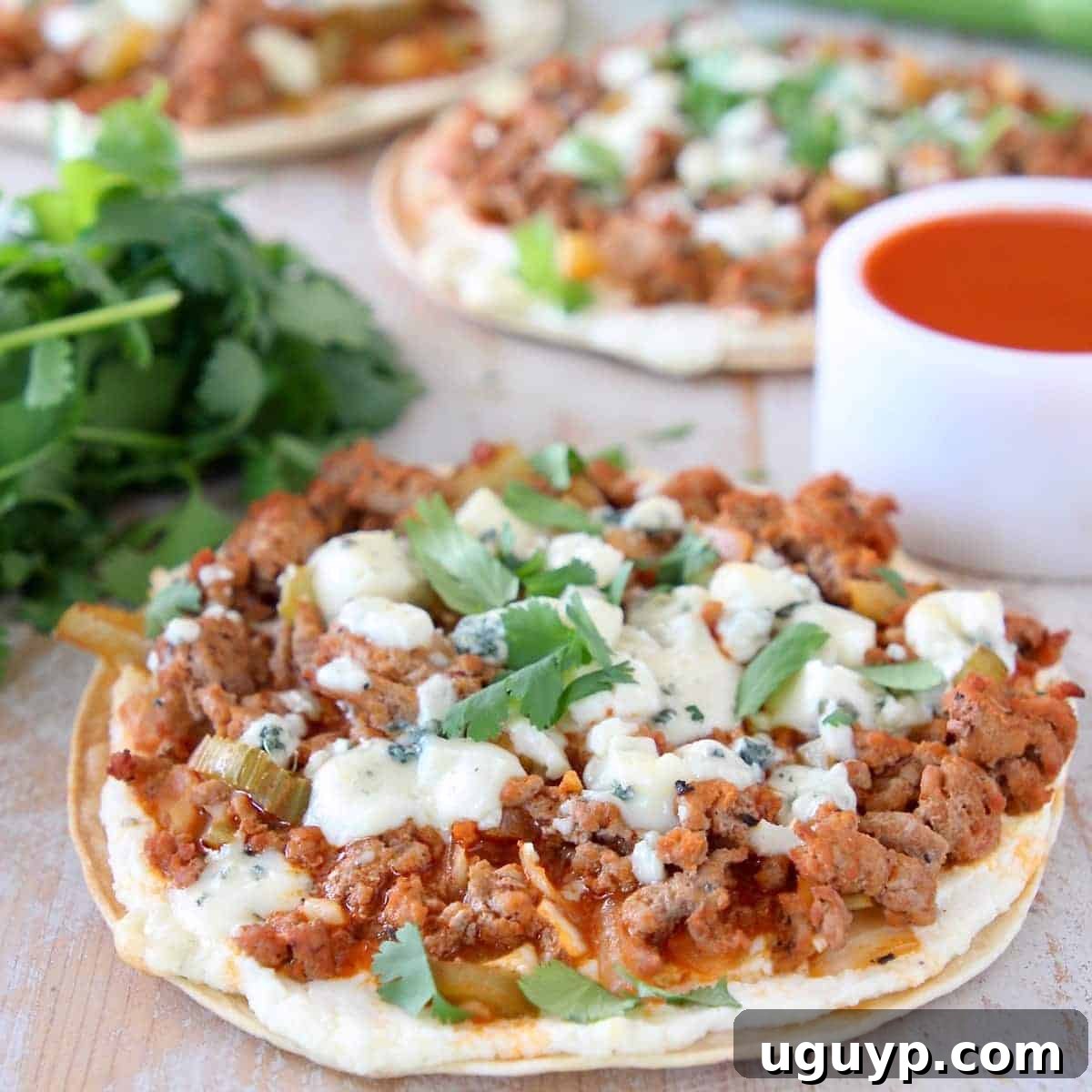 A delicious grilled tortilla flatbread topped generously with spicy buffalo sauce, savory ground turkey, and crumbled blue cheese, showcasing a perfect appetizer or meal.