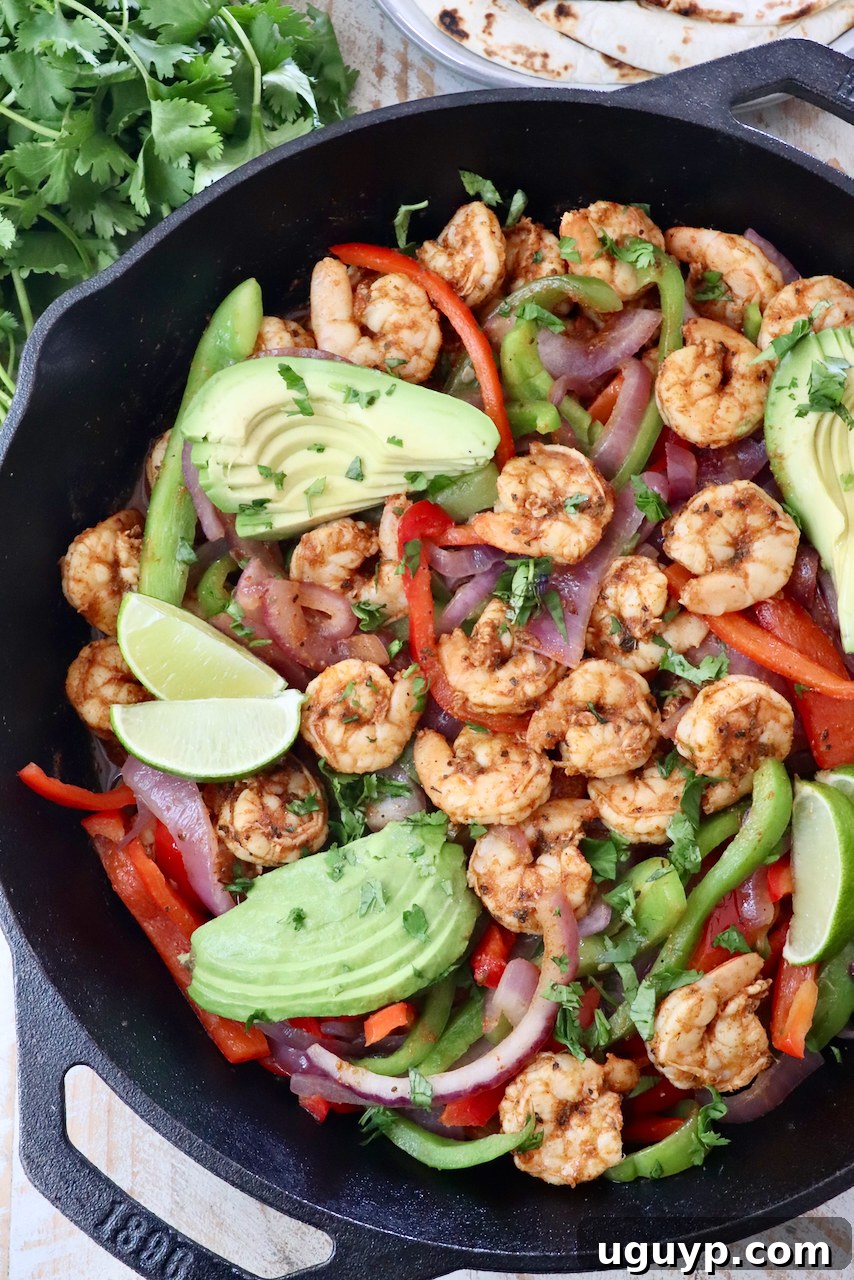 Sizzling shrimp fajitas in a cast iron skillet, garnished with sliced avocado and lime wedges.
