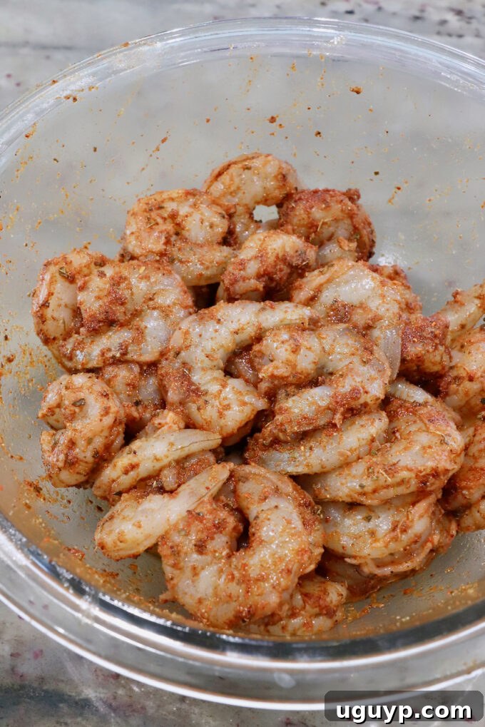 Seasoned raw shrimp in a glass bowl, ready for cooking.