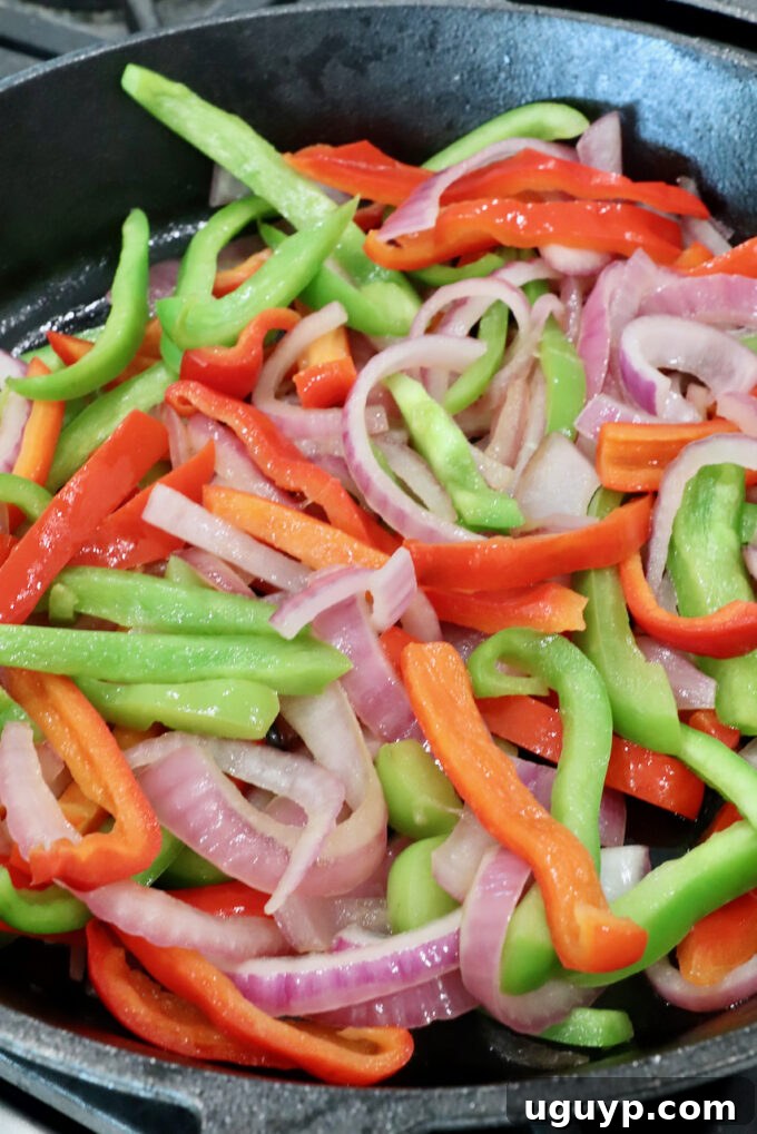 Sautéing bell peppers and onions in a skillet, showing vibrant colors and slight charring.