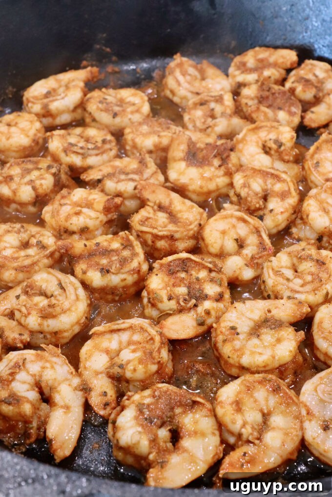 Cooked shrimp, perfectly pink and curled, in a cast iron skillet.