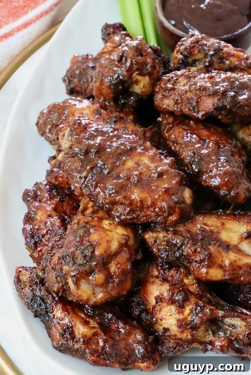 cooked chicken wings tossed in sauce stacked up on a plate
