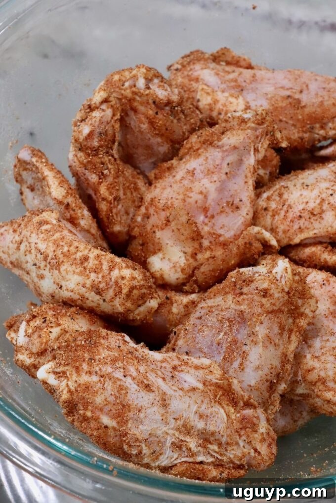 seasoned raw chicken wings in a glass bowl