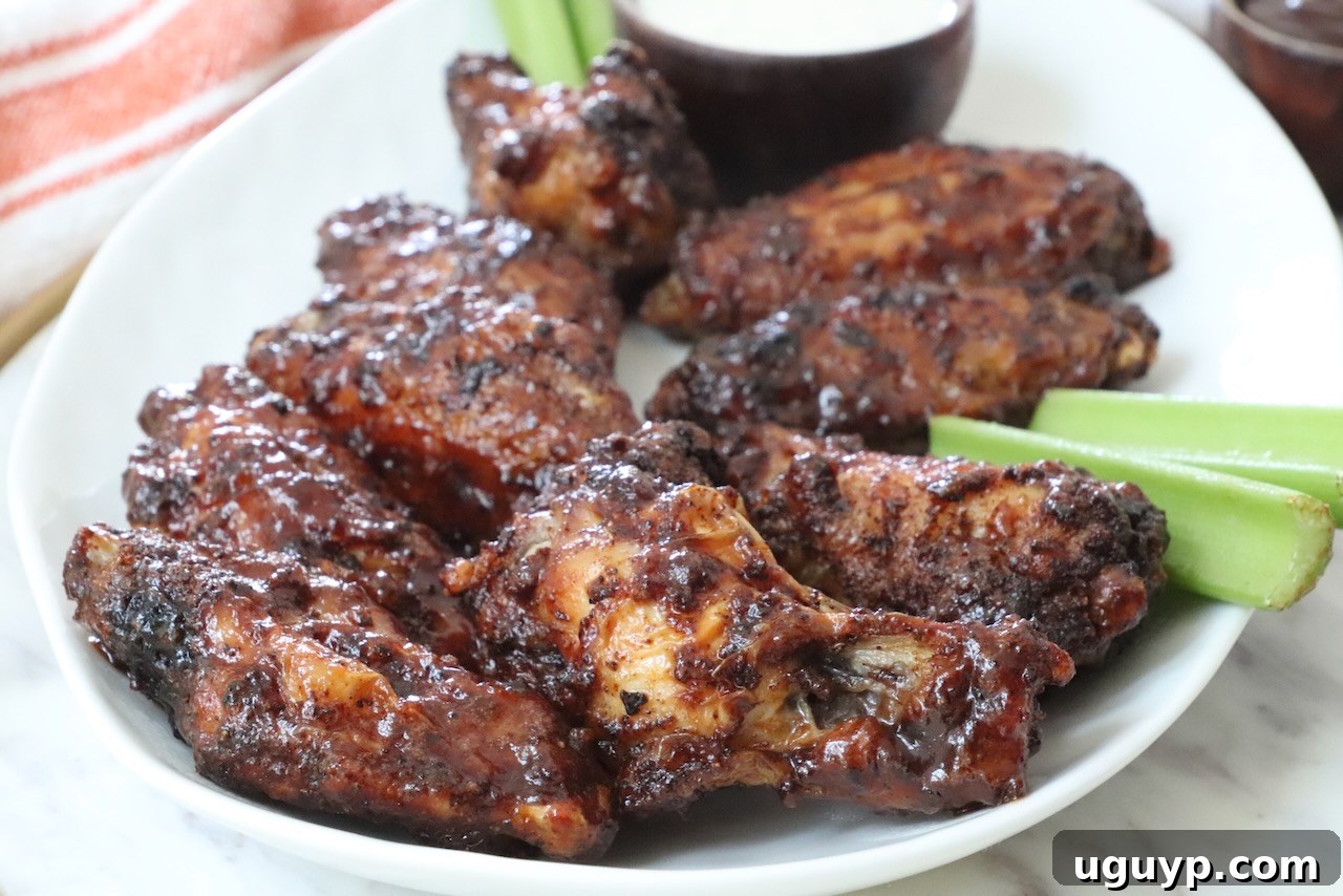 cooked chicken wings tossed in bbq sauce on a plate with celery sticks