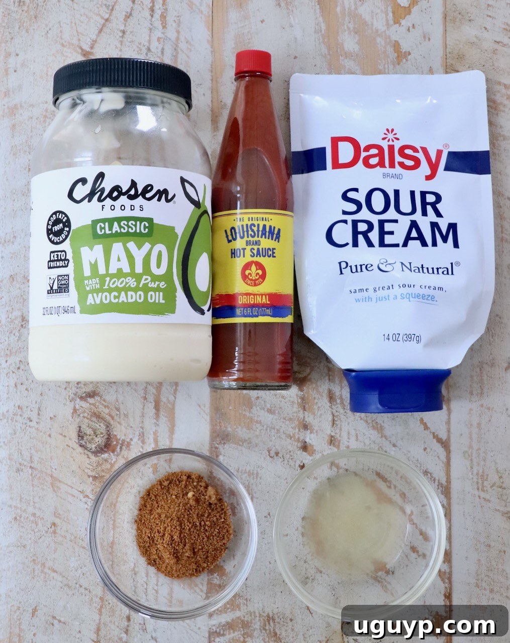 ingredients for creamy cajun sauce on a white wood board