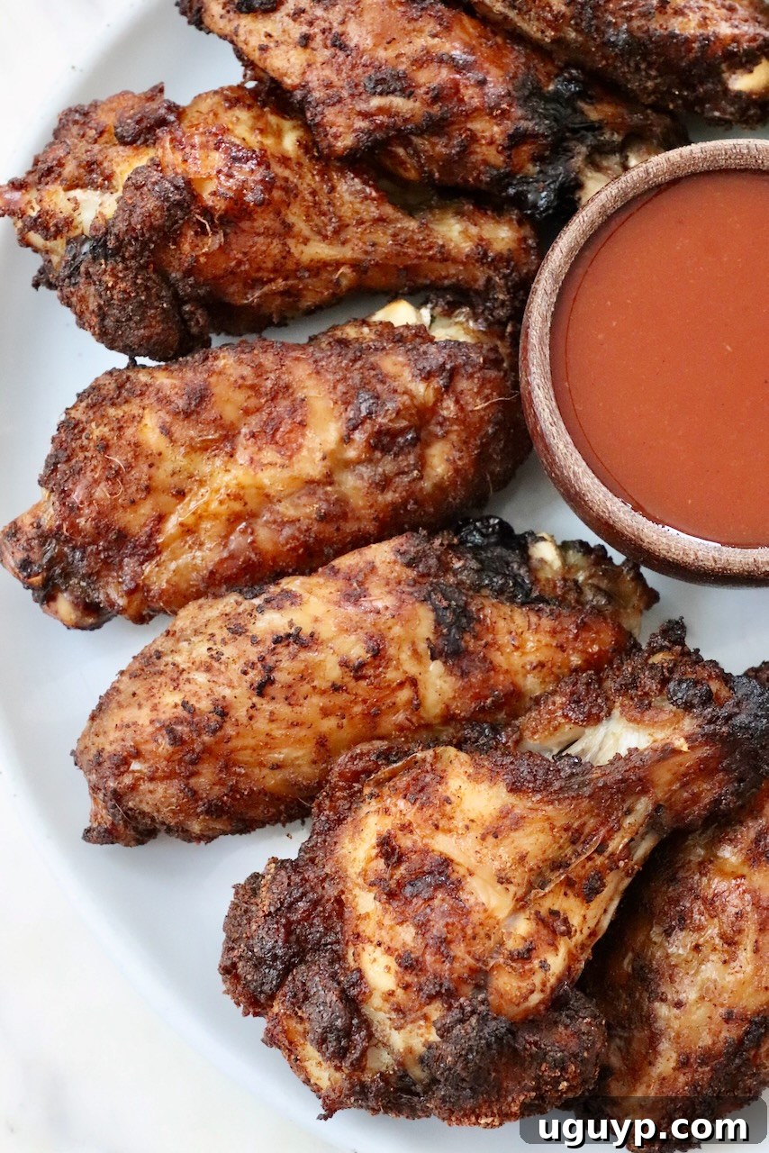 Perfectly crispy baked chicken wings on a plate, served with a side of buffalo sauce.