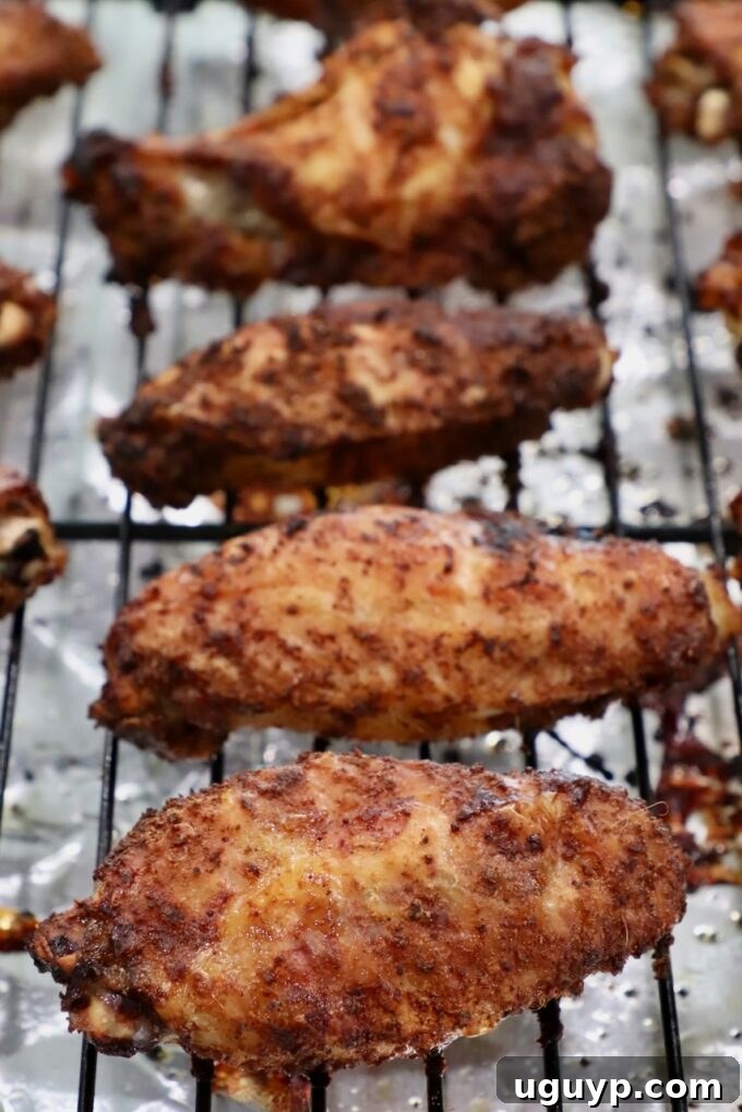Cooked, golden-brown chicken wings on a wire rack over a baking sheet, fresh out of the oven.