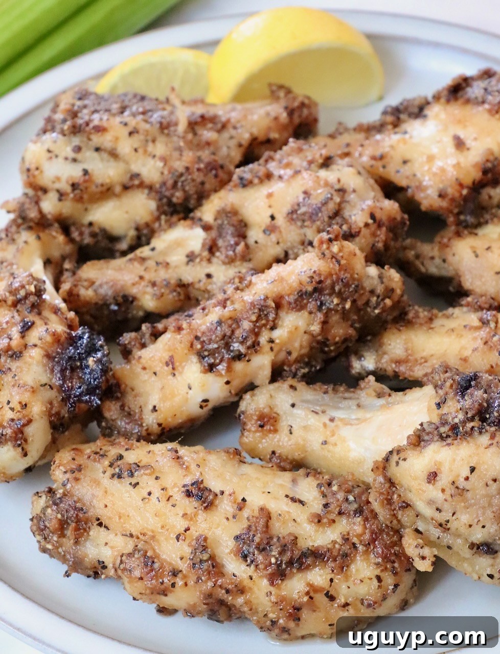 A plate of perfectly cooked lemon pepper chicken wings, glistening with butter and seasoning.