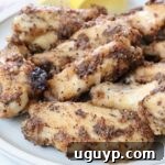 A small stack of cooked lemon pepper chicken wings on a plate, ready to be served.