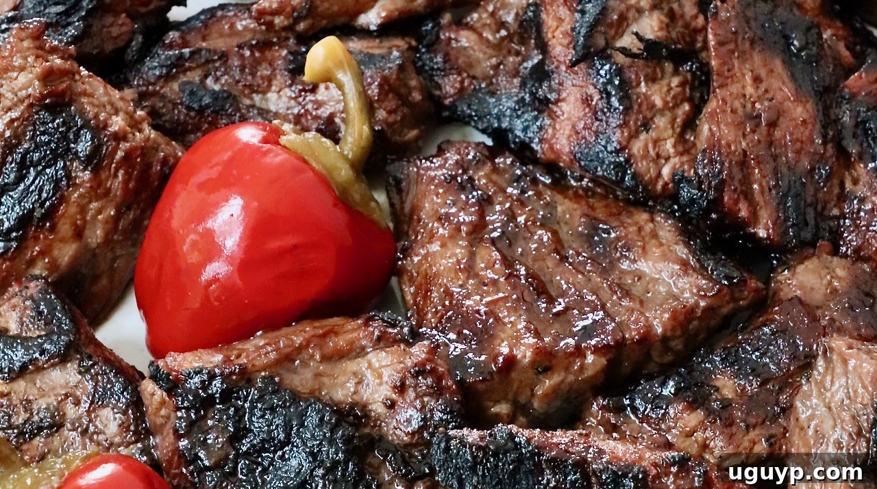 A stunning platter of grilled steak tips, garnished with vibrant cherry peppers, ready for a feast.