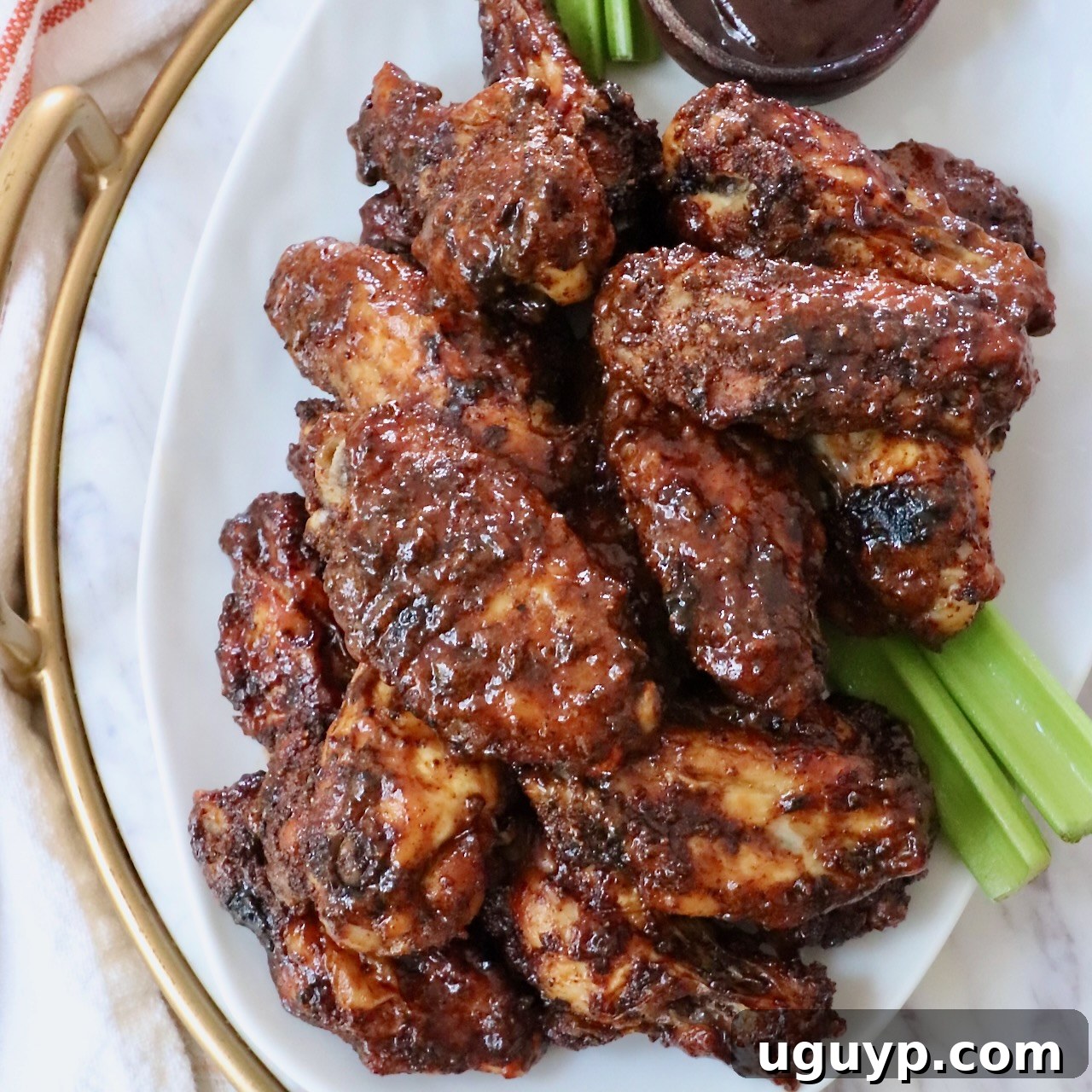Cooked chicken wings generously tossed in a rich BBQ sauce, piled high on a serving plate.