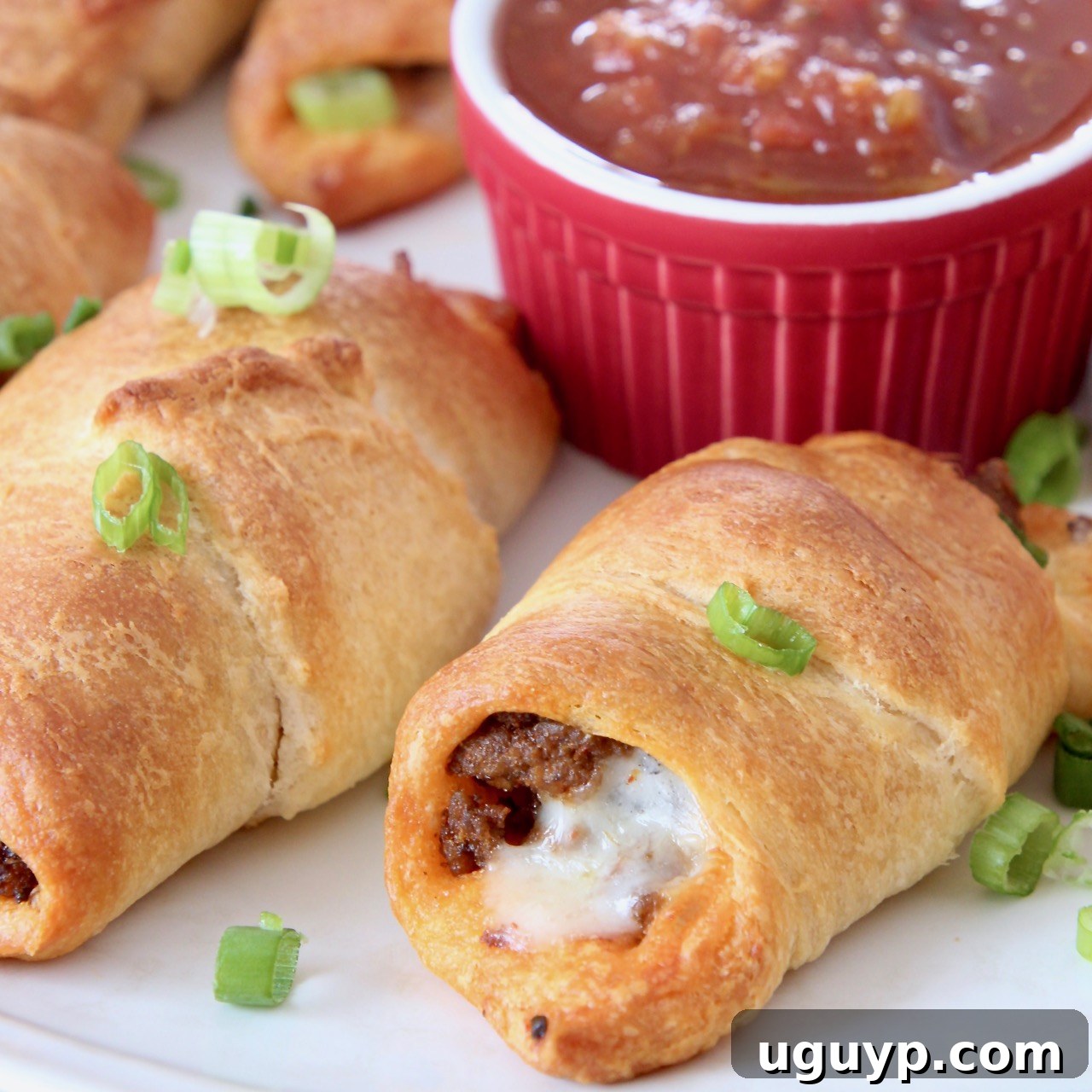 Baked Taco Crescent Rolls on a plate, filled with seasoned beef and cheese.